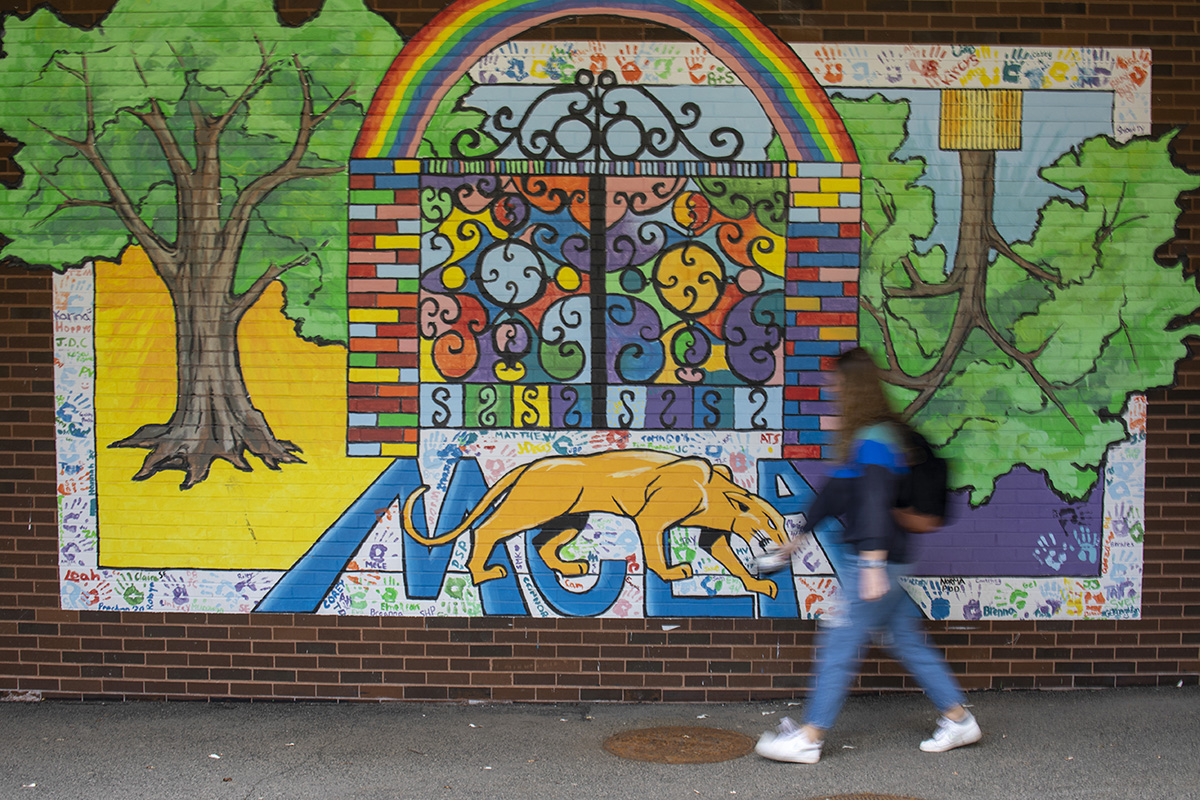 Student walking by MCAL mural