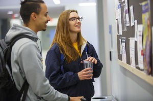 two student looking at a bulletin board